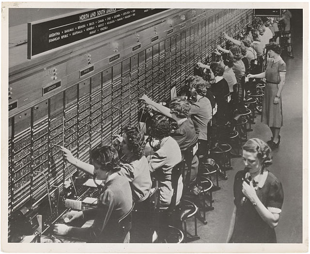 A line of women manning the lines of telephone communications.